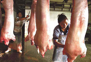 Workers process pork at a slaughterhouse in Zibo, Shandong province, on Monday.[China Daily]