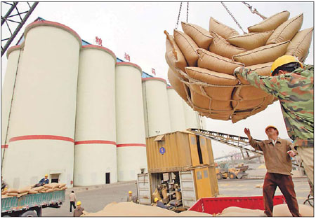 Workers unload imported soybeans at a harbor in China. The country imported a record 54.8 million tons of soybeans in 2010, compared with 15.2 million tons of domestic production, General Administration of Customs data showed. [China Daily]