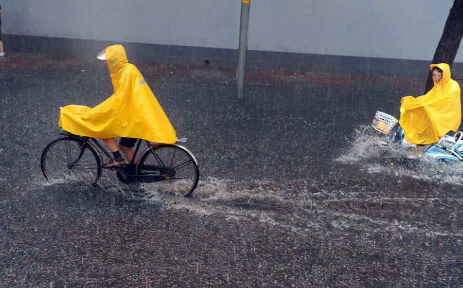 People ride in water on a street in Beijing, capital of China, June 23, 2011. Rainstorms pounded the Chinese capital Thursday afternoon. The storms delayed flights, slowed road traffic and disrupted the operation of two subway lines in the afternoon rush hours. [Xinhua]