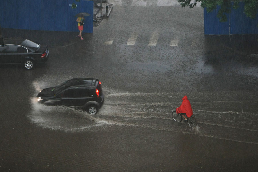 Riders and vehicles are seen in water on a street in Beijing, capital of China, June 23, 2011. Rainstorms pounded the Chinese capital Thursday afternoon. The storms delayed over 140 flights, slowed road traffic and disrupted the operation of two subway lines in the afternoon rush hours. [Xinhua]