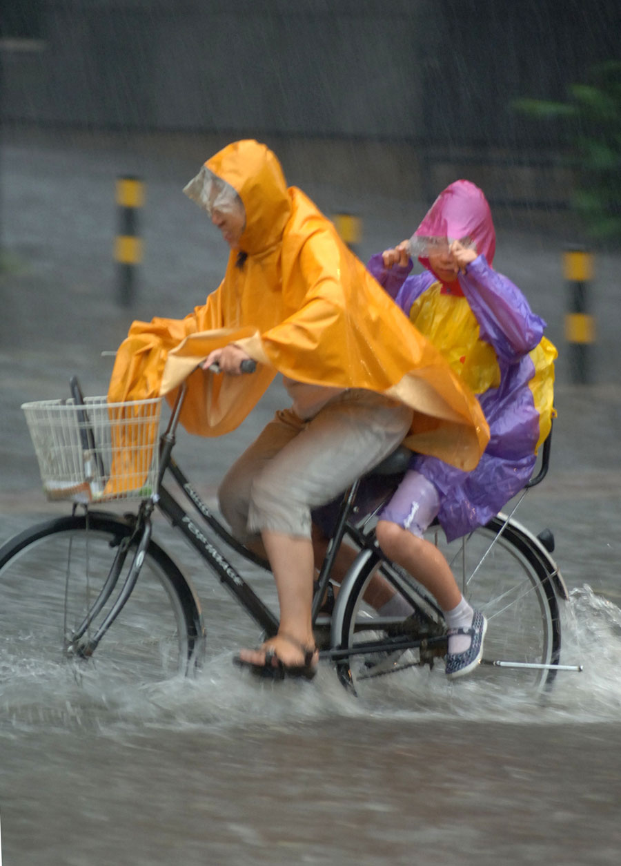 People ride in water on a street in Beijing, capital of China, June 23, 2011. Rainstorms pounded the Chinese capital Thursday afternoon. The storms delayed flights, slowed road traffic and disrupted the operation of two subway lines in the afternoon rush hours. [Xinhua]