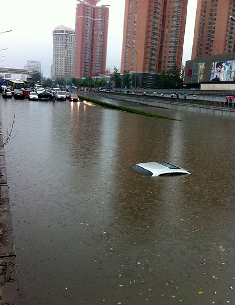 A car sinks in water on a street in Beijing, capital of China, June 23, 2011. Rainstorms pounded the Chinese capital Thursday afternoon. The storms delayed flights, slowed road traffic and disrupted the operation of two subway lines in the afternoon rush hours. [Xinhua] 