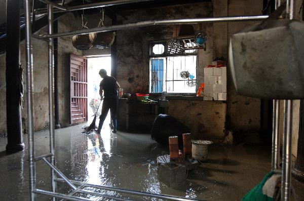 A villager cleans his flooded house in Sanjiangkou Village of Zhuji City, east China's Zhejiang Province, June 22, 2011.