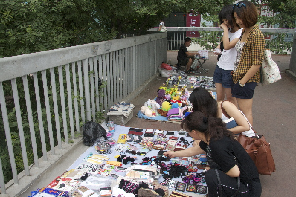 Tang shows potential customers the variety of trinkets she’s selling. On an average day, she’ll earn 100 yuan.