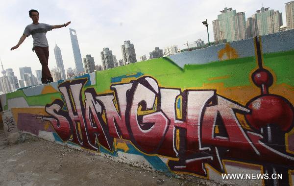 A man walks on top of a wall with graffiti in Shanghai, east China, June 23, 2011. A 300-meter-long graffiti was unveiled near the Bund in central Shanghai on Thursday.