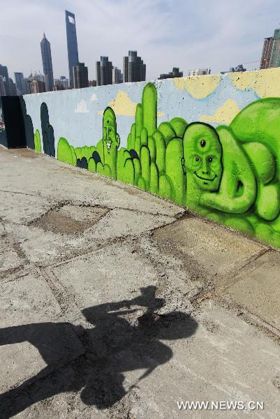 A photographer takes pictures of graffiti in Shanghai, east China, June 23, 2011. A 300-meter-long graffiti was unveiled near the Bund in central Shanghai on Thursday.