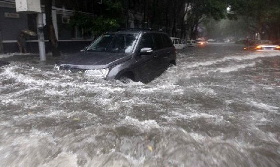 A car moves in water on a street in Beijing, capital of China, June 23, 2011. Rainstorms pounded the Chinese capital Thursday afternoon. The storms delayed flights, slowed road traffic and disrupted the operation of two subway lines in the afternoon rush hours