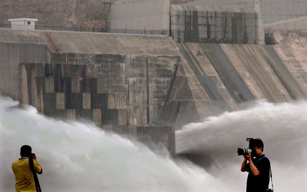 Photographers take photos as water gushes out from the Xiaolangdi Reservoir on the Yellow River in Central China's Henan province, June 22, 2011. [Photo/Xinhua]