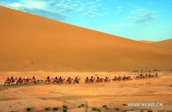 Tourists riding on camels visit Mingsha Mountain scenery zone in Dunhuang, northwest China's Gansu Province, June 24, 2011. Tourist volume and tourism industry income of the city reached 482,000 and 410 million RMB yuan (about 63.34 million U.S. dollars) respectively in the first five months of this year, 41 percent and 102.5 percent higher than the same period of the previous year respectively. [Xinhua/Zhang Weixian] 