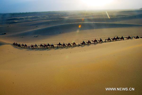 Tourists riding on camels visit Mingsha Mountain scenery zone in Dunhuang, northwest China's Gansu Province, June 24, 2011. Tourist volume and tourism industry income of the city reached 482,000 and 410 million RMB yuan (about 63.34 million U.S. dollars) respectively in the first five months of this year, 41 percent and 102.5 percent higher than the same period of the previous year respectively. [Xinhua/Zhang Weixian] 