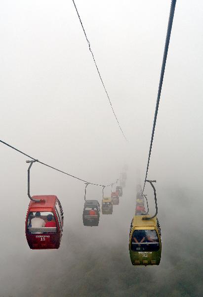 Passengers take cable cars moving amid the fog after a rainfall in the scenery spot of Laojunshan Mountain in Luanchuan County, central China's Henan Province, June 25, 2011. [Xinhua/Wang Song]
