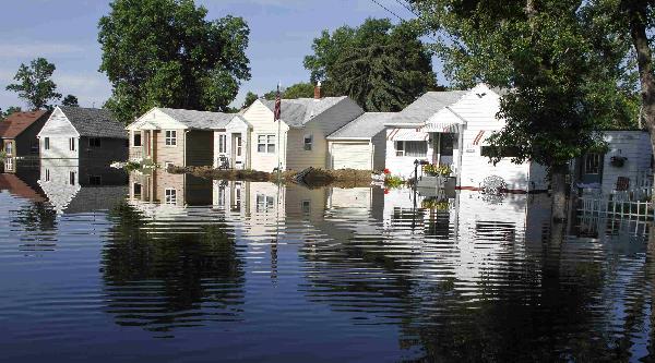 Homes seen in the morning light, are reflected in flood waters, with the earthen levee of one house (C) appearing to remain intact in Minot, North Dakota, June 25, 2011. The rapidly rising Souris River poured over flood defenses in Minot, overwhelming efforts to delay the deluge and forcing the immediate evacuation of thousands of homes. Flood projections have forecast about 18 more inches of water before levels begin dropping. [Xinhua/Reuters] 