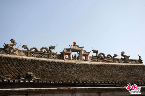 Carved figurines who foretell auspicious occasions stand on the roof of an old family house. 