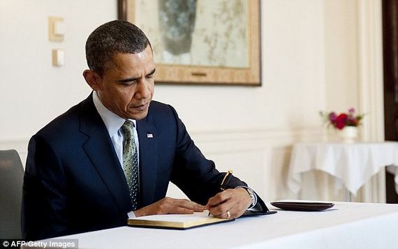 US President Barack Obama signs a book at the Japanese Embassy in Washington, DC, March 17, 2011, but he signed a BILL with an autopen.
