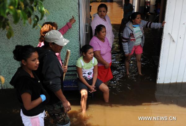 A family waits outside their home on a flooded street in the municipality of Nezahualcoyotl, the State of Mexico, Mexico, on June 27, 2011. 