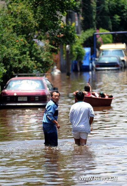 Residents walk on a flooded street in the municipality of Nezahualcoyotl, the State of Mexico, Mexico, on June 27, 2011. 