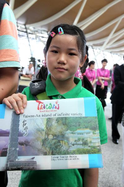 Eleven-year-old Yang Xinyan, member of a group of individual mainland tourists to southeast China's Taiwan, shows a travel handbook while waits for boarding at Shanghai Pudong International Airport in Shanghai, east China, June 28, 2011.