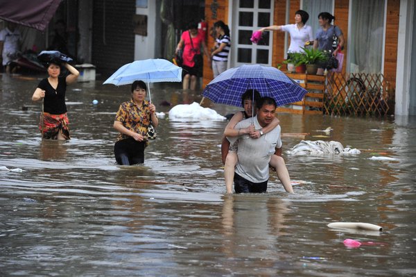 People wade through floodwaters on a street in Changsha, the capital of Central China's Hunan province, June 28, 2011.