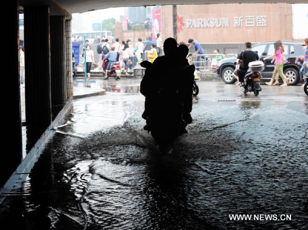 People rides in the water as heavy rainfall hit Changsha, capital of central China&apos;s Hunan Province, June 28, 2011. The traffic was disturbed as downpour hit the city on Tuesday. [Xinhua]