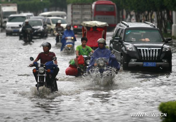 People wade on the flooded street as downpour hit Jinjiang City of southeast China&apos;s Fujian Province, June 28, 2011. Heavy rainfall seriously disturbed the city&apos;s traffic. [Xinhua] 