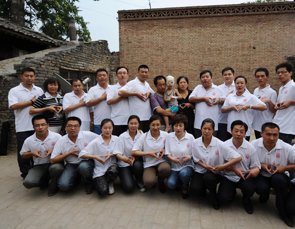 Volunteers pose for photos with the family of Xiangxiang, who has to wear a medical mask to help his face recover from horrific burns, in Fenyang city, North China's Shanxi province, June 24, 2011. 