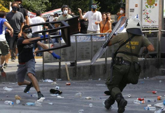 A protester (L) throws a chair at a riot policeman during violent protests against austerity measures in Athens, June 28, 2011. With Greece teetering on the brink of bankruptcy, parliament is due to vote this week on a package of spending cuts, tax increases and privatisations agreed as part of a massive bailout aimed at averting the euro zone's first default.