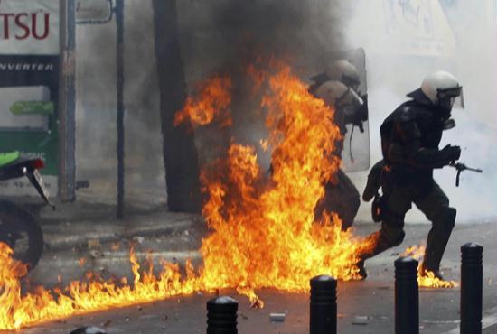 Riot police advance through the flames from a molotov cocktail during protests against austerity measures in Athens, June 28, 2011.