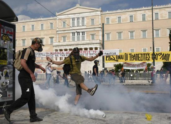 A demonstrator kicks a teargas canister in front of parliament during protests against austerity measures in Athens, June 28, 2011.