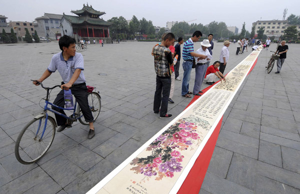 A 90-meter-long piece of calligraphy and painting is displayed at a square in Luoyang, Central China's Henan province, on June 27, 2011. 