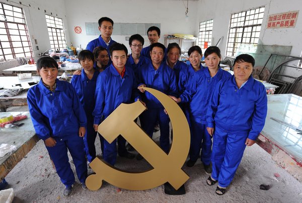 Workers pose with a newly-made emblem of the Communist Party of China (CPC) in a factory in Anqing city, East China's Anhui province, June 28, 2011, ahead of the CPC's 90th anniversary. 
