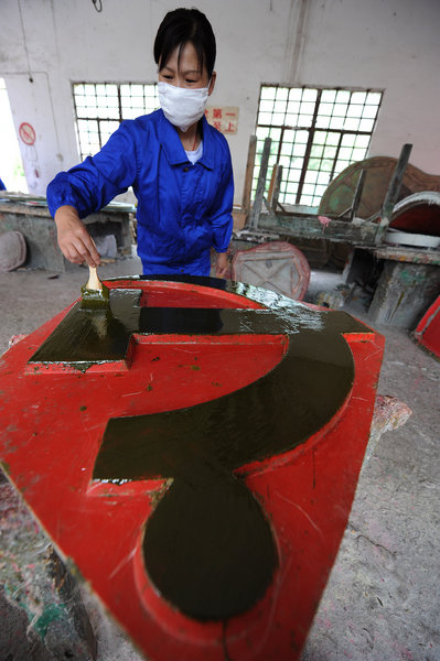 A woman casts a Party emblem in a factory in Anqing city, East China's Anhui province, June 28, 2011.