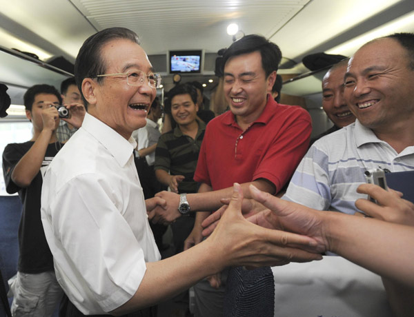  Premiere Wen Jiabao shakes hands with other passengers while travelling on the first bullet train of the landmark high-speed railway from Beijing to Shanghai, June 30, 2011. 