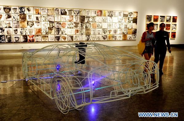 Visitors walk past the exhibited art works at an art show celebrating the 90th anniversary of the founding of the Communist Party of China (CPC) in Hangzhou, capital of east China's Zhejiang province, June 30, 2011.