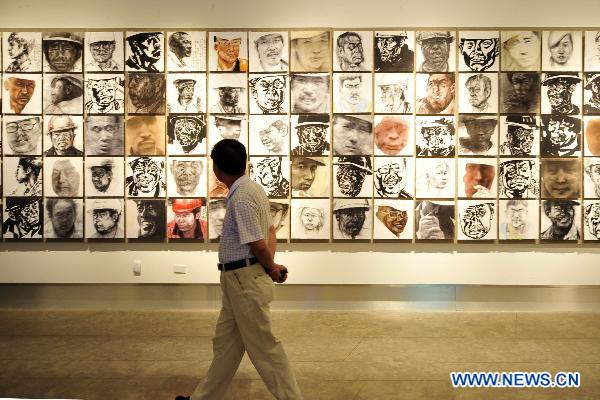 A visitor walks past the exhibited art works at an art show celebrating the 90th anniversary of the founding of the Communist Party of China (CPC) in Hangzhou, capital of east China's Zhejiang province, June 30, 2011. 