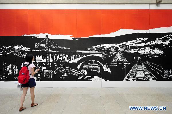 A visitor looks at the exhibited painting at an art show celebrating the 90th anniversary of the founding of the Communist Party of China (CPC) in Hangzhou, capital of east China's Zhejiang province, June 30, 2011. 