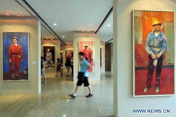 Visitors walk past the exhibited art works at an art show celebrating the 90th anniversary of the founding of the Communist Party of China (CPC) in Hangzhou, capital of east China's Zhejiang province, June 30, 2011. 