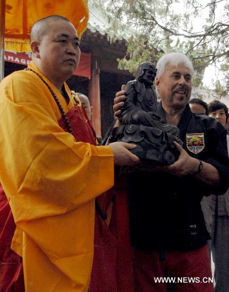 Shi Yongxin (L), current abbot of the Shaolin Temple, presents a sculpture of Bodhidharma to Professor Charles Mattera of United Studios of Self Defense (USSD) from the United States at the Shaolin Temple in Dengfeng, central China's Henan Province July 3, 2011. A group of 138 members of USSD visited the Shaolin Temple, the birthplace of modern martial arts and performed with Shaolin monks on Sunday. [Li Bo/Xinhua]