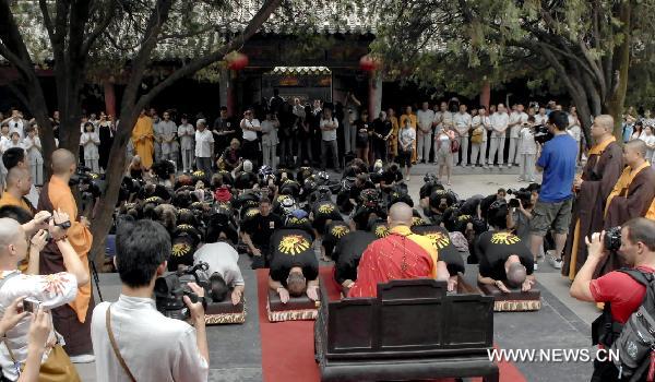 Members of United Studios of Self Defense (USSD) from the United States kowtow to Shi Yongxin (C), current abbot of the Shaolin Temple, at the Shaolin Temple in Dengfeng, central China's Henan Province July 3, 2011. A group of 138 members of USSD visited the Shaolin Temple, the birthplace of modern martial arts and performed with Shaolin monks on Sunday. [Li Bo/Xinhua]