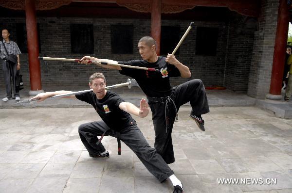 Two members of United Studios of Self Defense (USSD) from the United States performs martial arts at the Shaolin Temple in Dengfeng, central China's Henan Province July 3, 2011. A group of 138 members of USSD visited the Shaolin Temple, the birthplace of modern martial arts and performed with Shaolin monks on Sunday. [Li Bo/Xinhua]