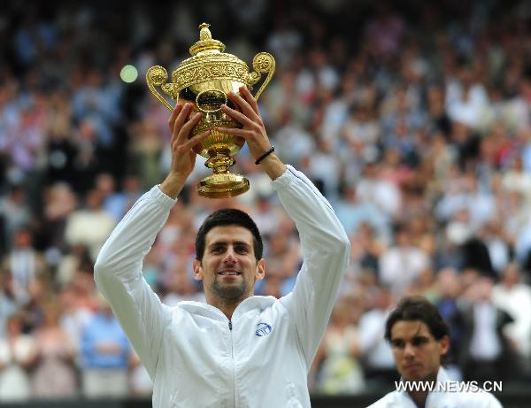 Novak Djokovic of Serbia raises the trophy after winning the final of men's singles against Rafael Nadal of Spain in 2011 Wimbledon tennis championships in London July 3, 2011. (Xinhua/Zeng Yi) 