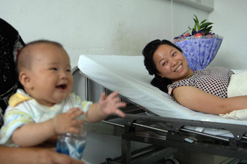 Rescuer Wu Juping smiles at her own son in a ward of the Traditional Chinese Medicine Bone Fracture Hospital at Fuyang, a county-level city in Hangzhou, East China's Zhejiang province, on Sunday, July 3, 2011 after she has saved a 2-year-old girl. [Photo: Xinhua] 