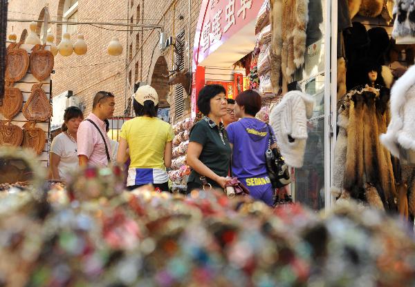 Tourists shop at the International Grand Bazaar in Urumqi, capital of northwest China's Xinjiang Uygur Autonomous Region, July 4, 2011. The International Grand Bazaar in Urumqi, trading a wide range from handicraft items to fruits and fashion clothing, has become the largest collecting and distributing center for goods in Central Asia. [Xinhua/Wang Fei] 