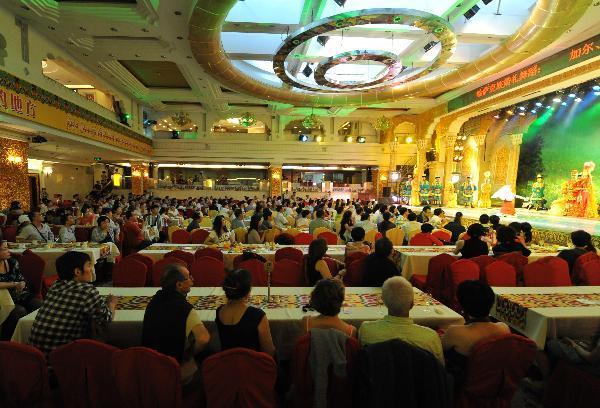 Actresses perform for tourists in a banquet hall at the International Grand Bazaar in Urumqi, capital of northwest China's Xinjiang Uygur Autonomous Region, July 4, 2011. The International Grand Bazaar in Urumqi, trading a wide range from handicraft items to fruits and fashion clothing, has become the largest collecting and distributing center for goods in Central Asia. [Xinhua/Wang Fei]