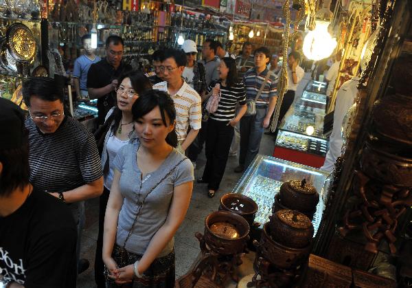 Tourists shop at the International Grand Bazaar in Urumqi, capital of northwest China's Xinjiang Uygur Autonomous Region, July 4, 2011. The International Grand Bazaar in Urumqi, trading a wide range from handicraft items to fruits and fashion clothing, has become the largest collecting and distributing center for goods in Central Asia. [Xinhua/Wang Fei]