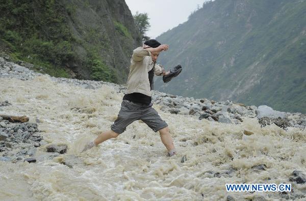 A man walks on a highway damaged by rain-triggered mudslides in Wenchuan County, southwest China&apos;s Sichuan Province, July 4, 2011. State Highway 213 was referred to as a &apos;lifeline&apos; by rescue workers following the devastating 2008 Wenchuan earthquake. The recent continuous heavy downpours have caused mud-and-rock slides, which cut off the highway in a number of sections. [Xinhua] 