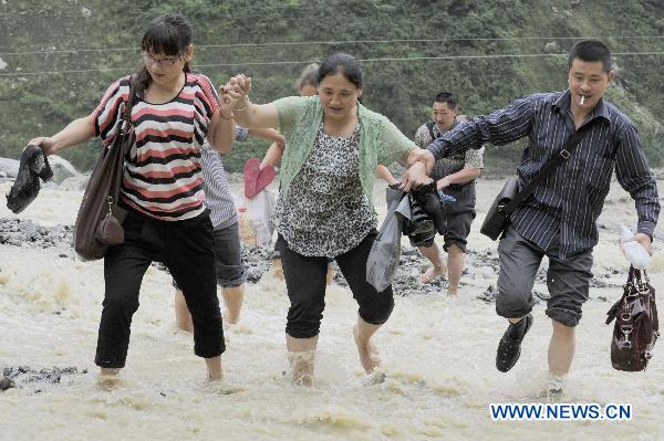Local residents walk on a highway damaged by rain-triggered mudslides in Wenchuan County, southwest China&apos;s Sichuan Province, July 4, 2011.