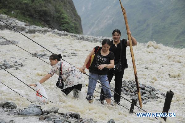 Three local residents walk on a highway damaged by rain-triggered mudslides in Wenchuan County, southwest China&apos;s Sichuan Province, July 4, 2011.