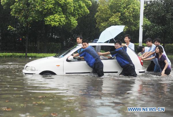 People push a stalled car on a waterlogged street in Yangzhou, east China&apos;s Jiangsu Province, July 5, 2011. A heavy rainfall caused the flood in Yangzhou on Tuesday.