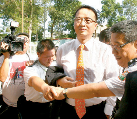 Security guards escort Wang Zheng, a major shareholder of Asia Television Limited (ATV), outside the station's headquarters in Tai Po on Thursday afternoon. Questions were thrown at him by journalists about ATV's false report on the former president of China. Wang said he only knew of the matter after the television broadcaster aired the news.