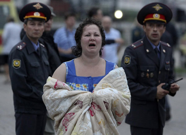 A survivor (C) from the Bulgaria tourist boat that sank walks while wrapping herself with a blanket after the arrival at the port of Kazan July 10, 2011. [Agencies] 